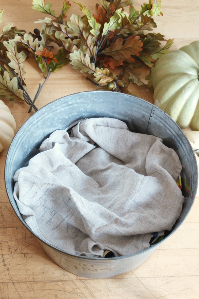 Galvanized metal bucket filled with crumpled newspaper and a linen towel to raise up pumpkins.