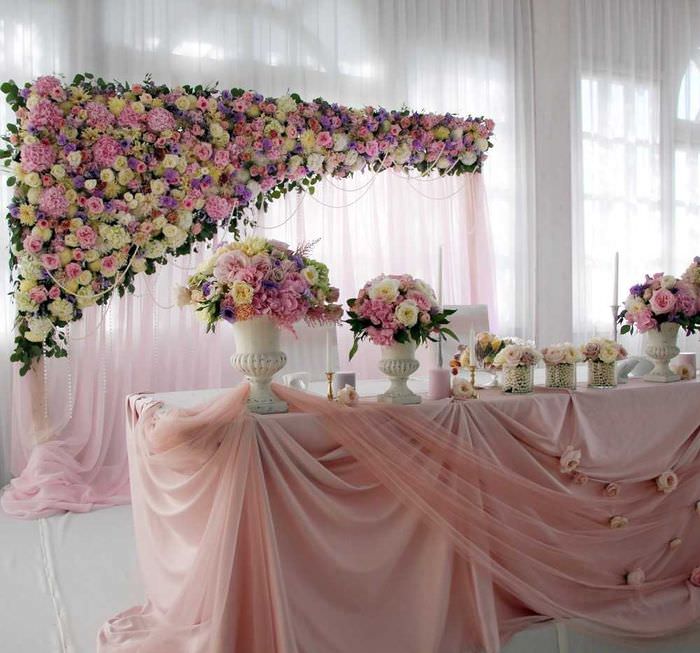 Оформление свадебного стола светлыми цветами и полупрозрачной тканью
