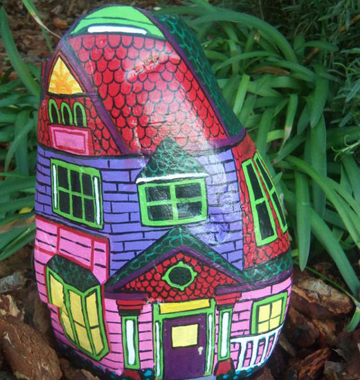 Яркий нарисованный домик на камне сада 
